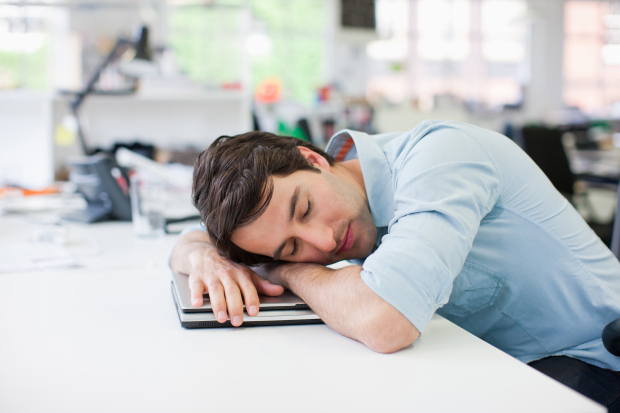 Businessman sleeping on laptop at desk in office