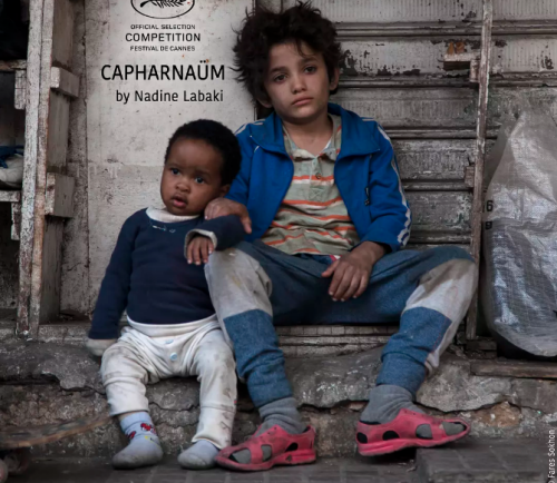 A scene in Capernaum, Zain and Yonus sit beside the street 