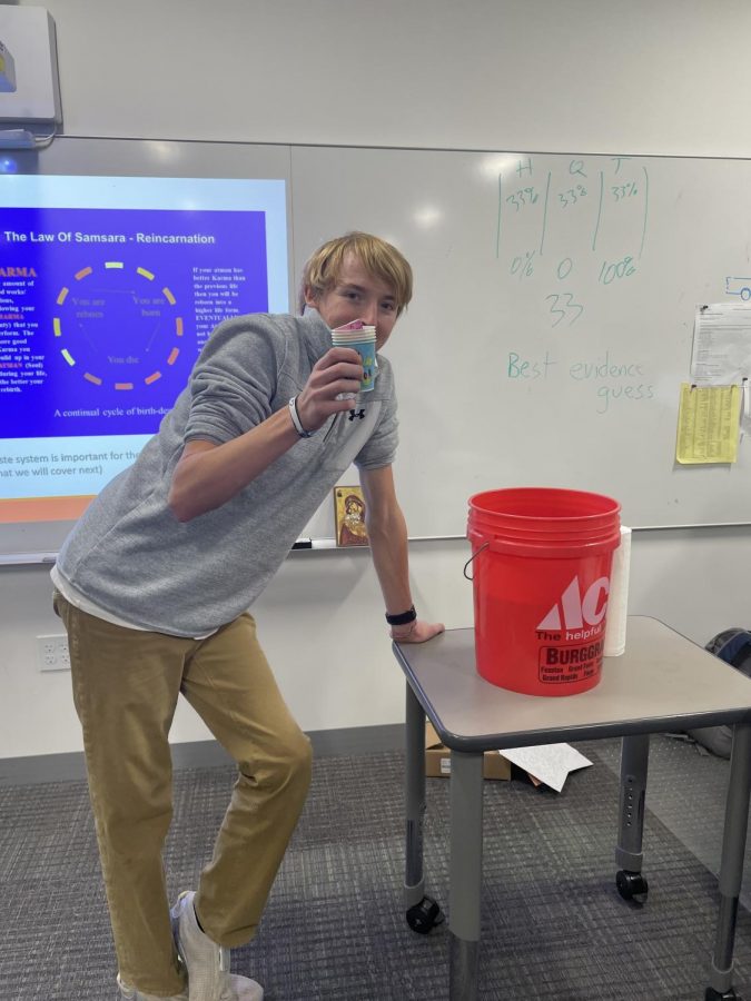 Payton Weifenbach poses with cups and a bucket in Mr. McGlaun's World Religions class