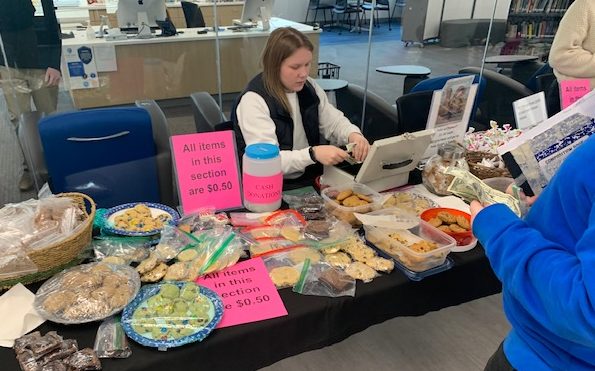 Hailey Biesanz mans the table before school at the bake sale to benefit Sajidas family