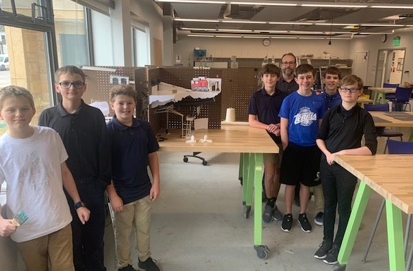 Jacob Moore, Reece Pronschinske, Will Peterson, Jack Slaggie, Mr. Paulsen, Carter Knuesel, Jaxson Greshik, and Zephyr Paulsen in their workshop in the physics/art room classroom on the first floor of the St. Joseph building