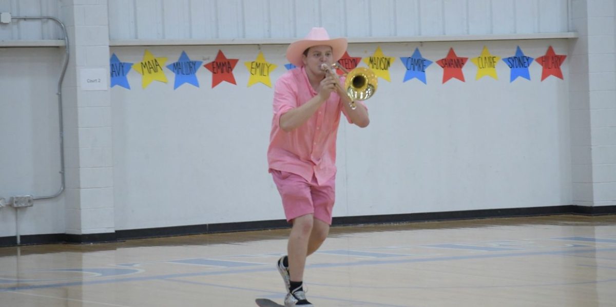 Finn Blagborne plays the Cotter fight song as he skateboards through the gym at the pep fest to fire up the troops