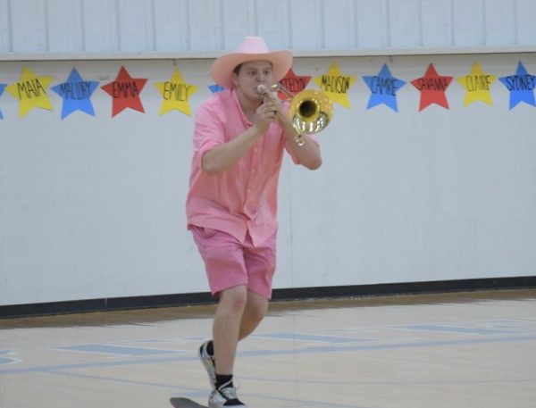 Finn Blagborne plays the Cotter fight song as he skateboards through the gym at the pep fest to fire up the troops